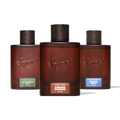 Three Squatch fragrance bottles arranged in a row against a solid green background. The center bottle is upright and labeled 'Squatch Fireside Bourbon', while the left and right bottles are slightly angled backward and labeled 'Squatch Rainforest Mist' and 'Squatch Glacial Falls' respectively.